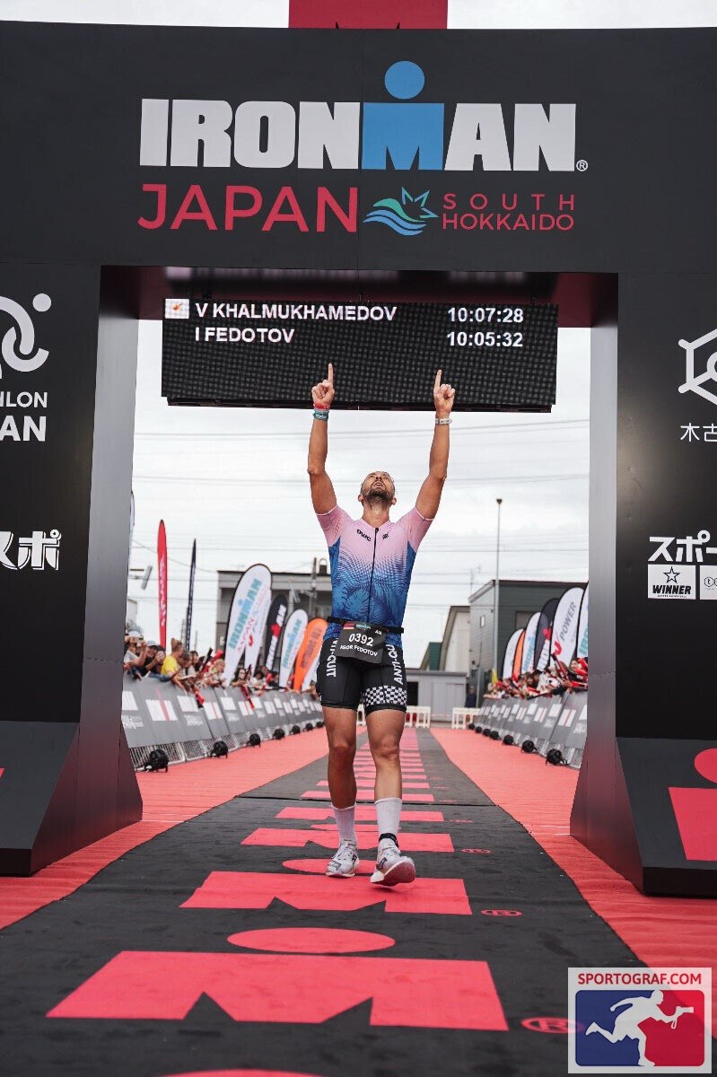 Игорь Федотов поднимает руки на финише IRONMAN Japan